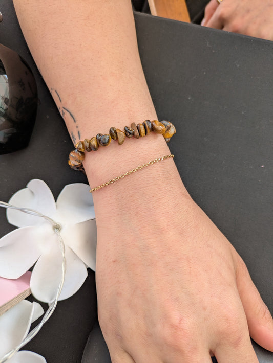 Hand wearing two bracelets on a dark surface with white flowers. One is beaded, and one is The Dublin 1.8mm Diamond-Cut Rope Chain Premium Permanent Jewellery.