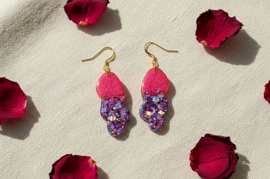 Handmade 'Billie' wavy resin dangle earrings in hot pink and purple holographic glitter on cream linen with rose petals — bold statement jewellery by Created By Lau, Yorkshire