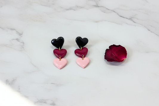 Handmade 'Hart' triple heart polymer clay dangle earrings in black, deep red and pink on pale marble — bold one-of-a-kind accessories by Created By Lau, Yorkshire