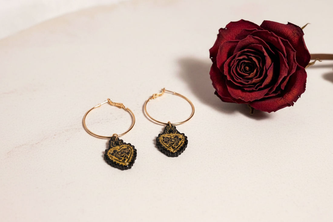 Handmade 'Simone' resin burning heart hoop earrings in black and gold on pale stone with a dried red rose — bold one-of-a-kind jewellery by Created By Lau, Yorkshire