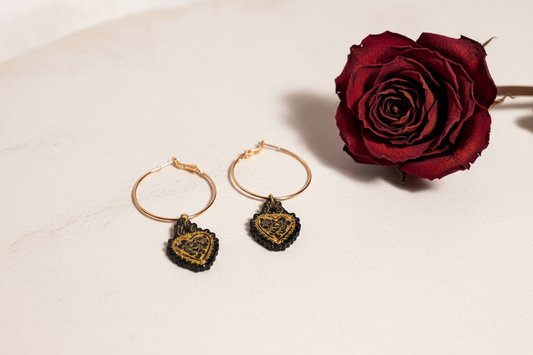 Handmade 'Simone' resin burning heart hoop earrings in black and gold on pale stone with a dried red rose — bold one-of-a-kind jewellery by Created By Lau, Yorkshire