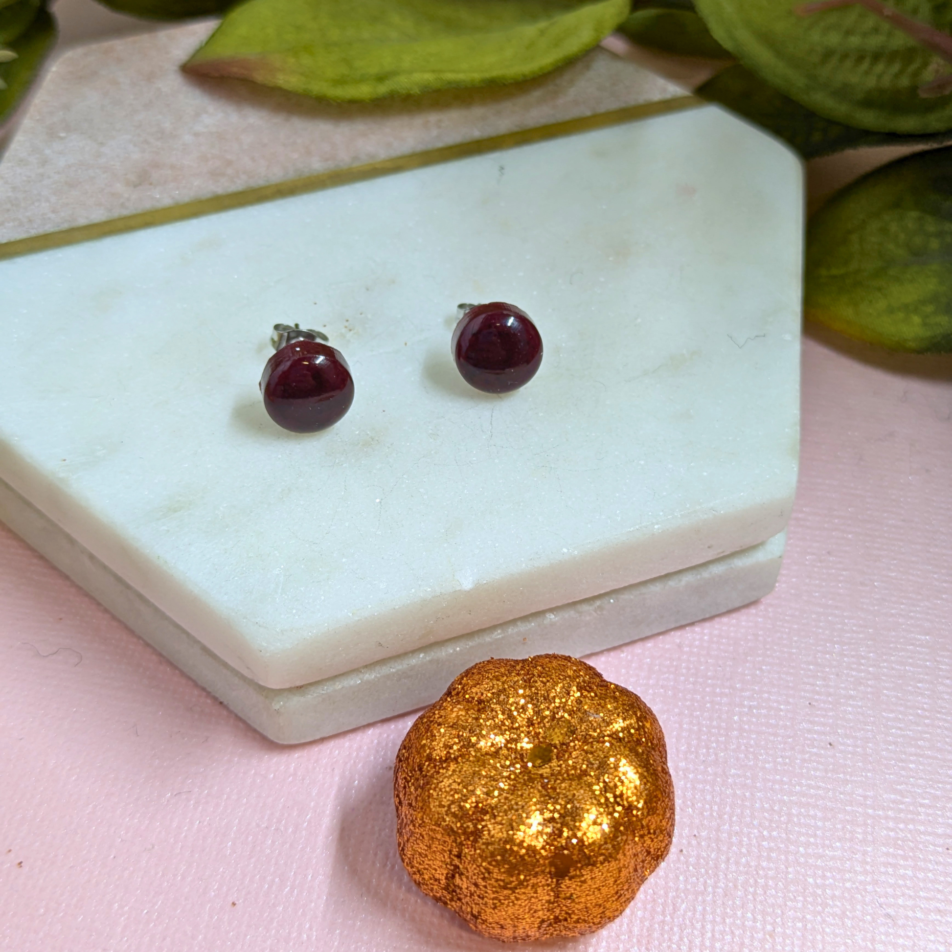 Bridget Blood Red small resin stud earrings by Created By Lau, displayed on a marble tray with autumnal styling — deep red glossy dome studs with stainless steel fittings"