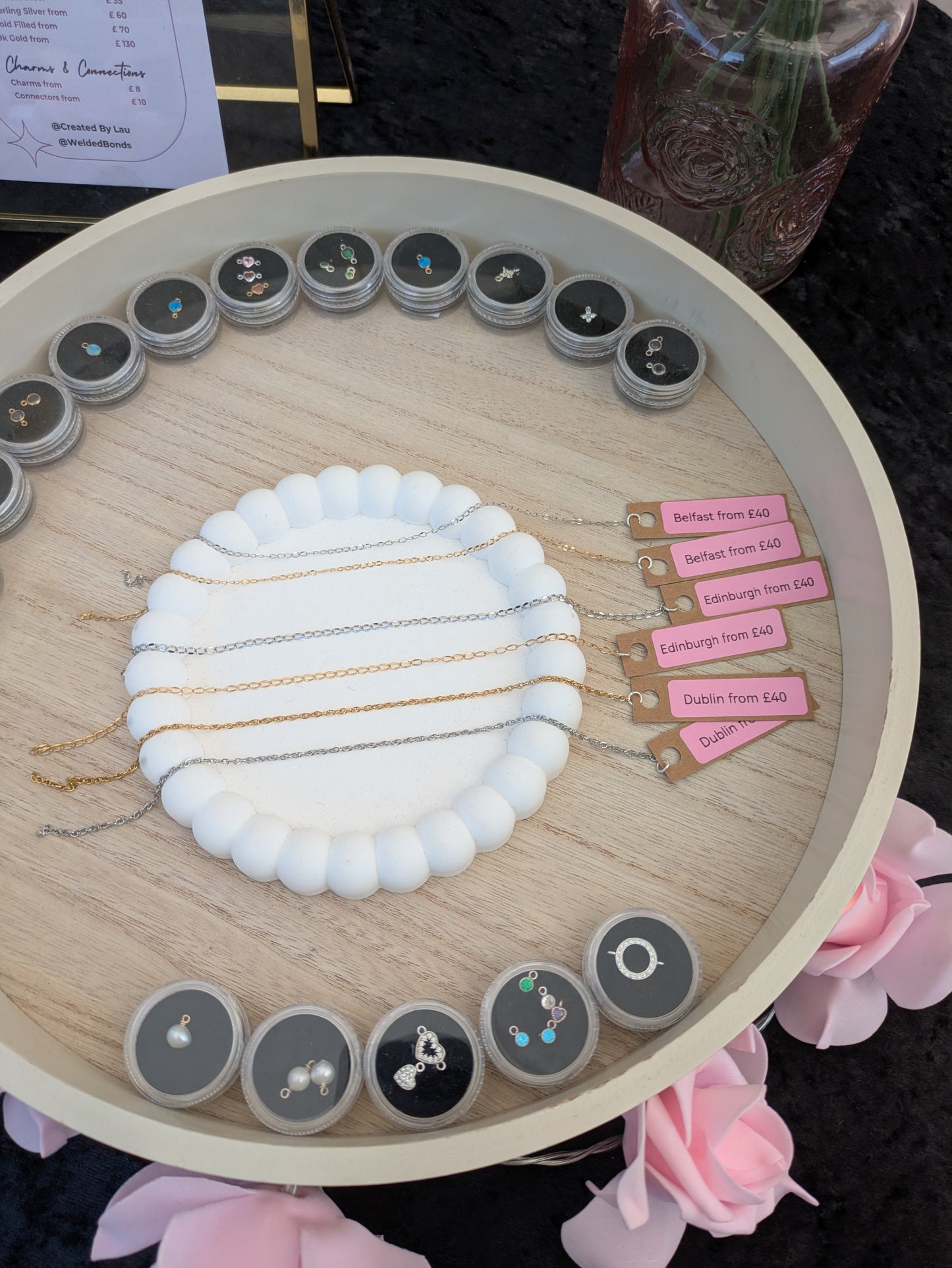 Wooden circular organiser with Premium Permanent Jewellery and decorative elements on a dark surface.