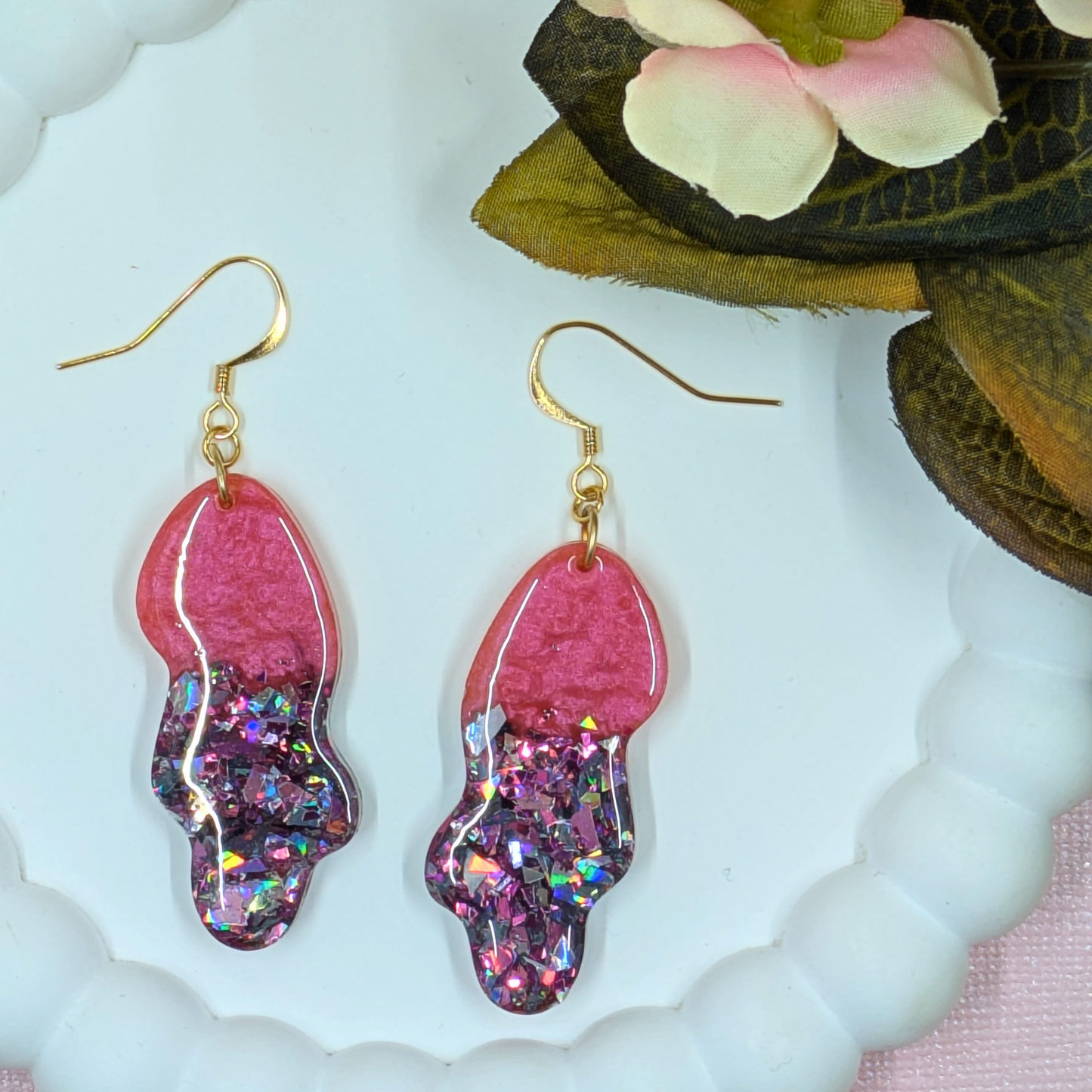 Close up of handmade wavy resin earrings showing red mica and blue shard glitter shimmer detail