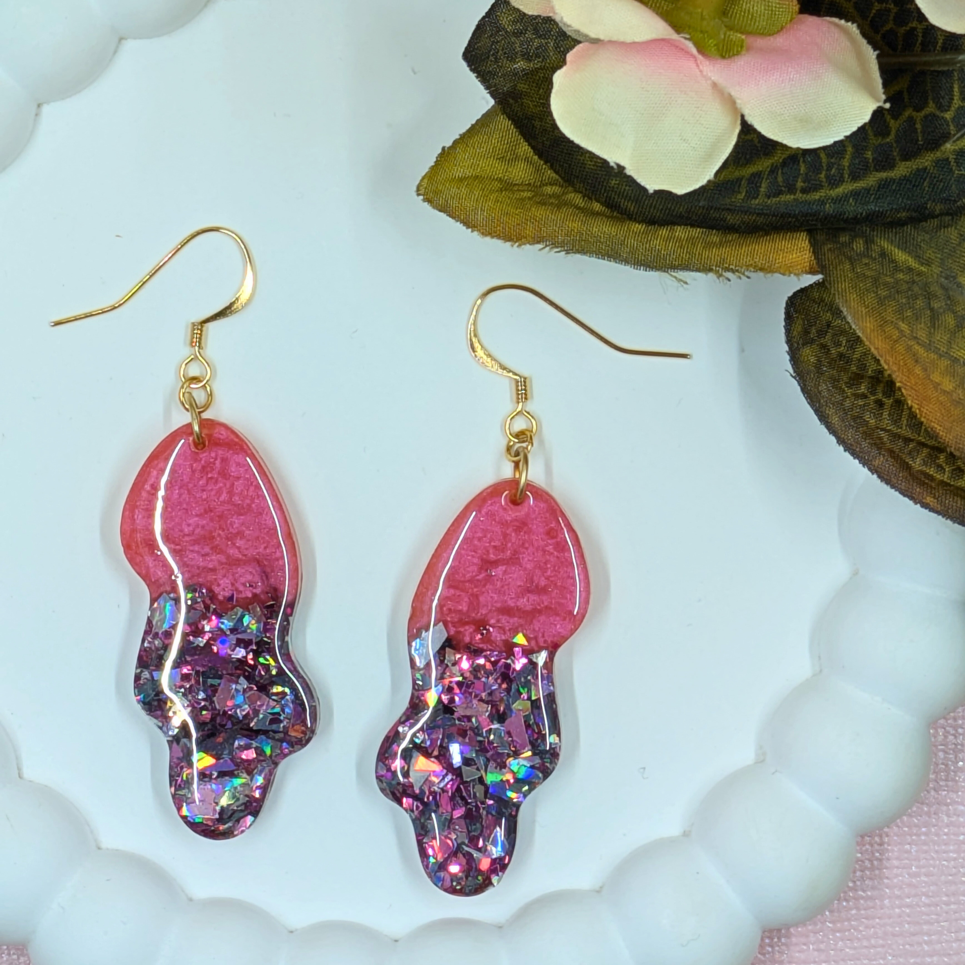Close up of handmade wavy resin earrings showing red mica and blue shard glitter shimmer detail