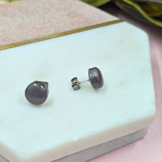 Close up of handmade bronze resin stud earrings showing unique resin pattern and stainless steel posts