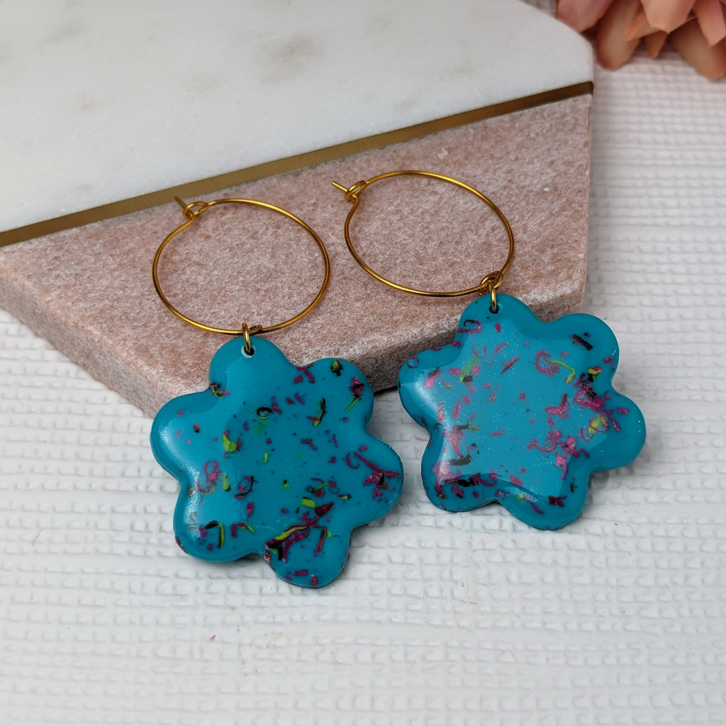 Close-up detail of turquoise polymer clay flower earrings showing colourful sprinkle detail and glossy resin finish on gold hoop hooks