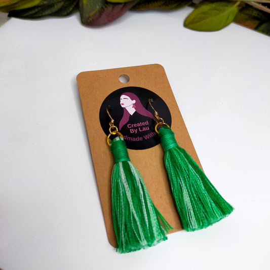 A pair of green ombre tassel earrings on a cardboard display, with a gold-plated or silver-plated finding and hook.